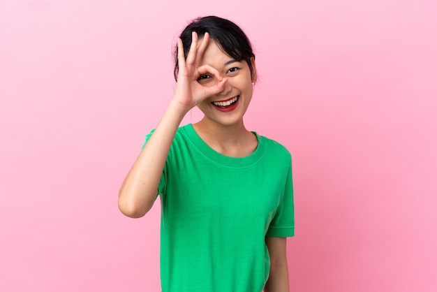 Joven mujer vietnamita aislada sobre fondo rosa mostrando signo ok con los dedos