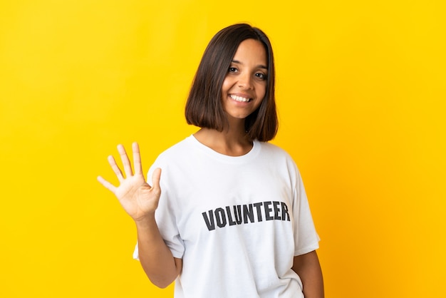 Joven mujer voluntaria aislada en amarillo contando cinco con los dedos