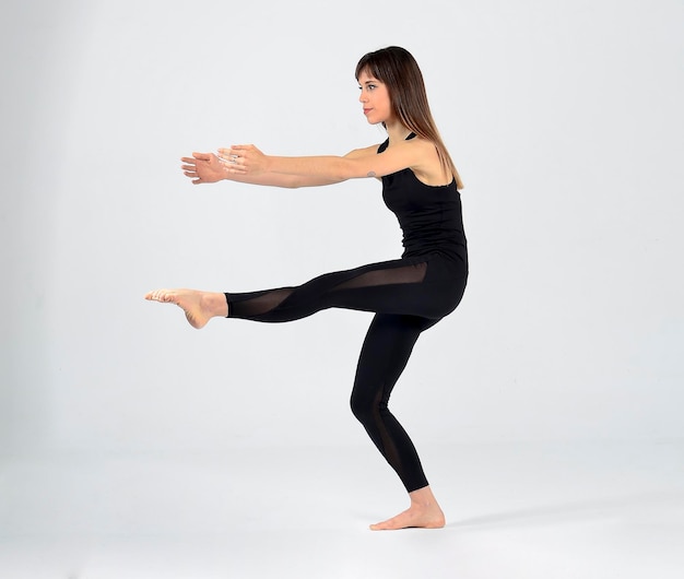 Joven mujer yogui deportiva practicando yoga, haciendo pose, haciendo ejercicio, usando ropa deportiva negra