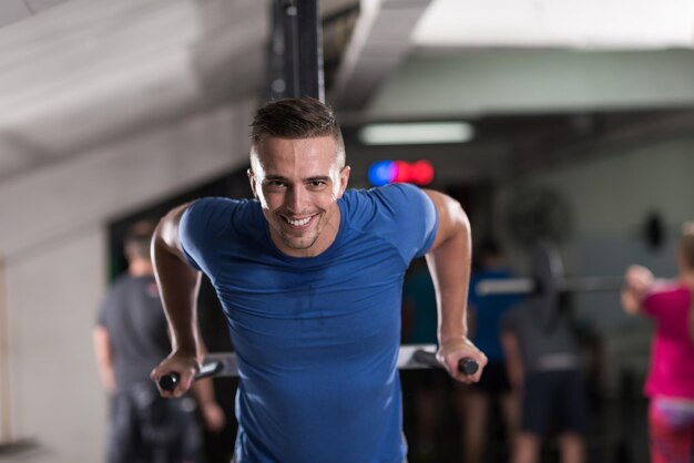 Joven musculoso culturista trabajando en el gimnasio haciendo ejercicios de barras paralelas Concept sport