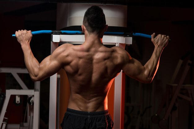 Joven musculoso haciendo ejercicio en el gimnasio