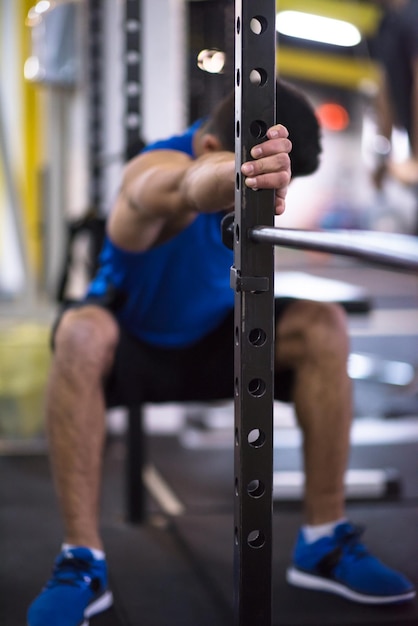 Foto joven musculoso haciendo pull ups en la barra vertical como parte de cross fitness training