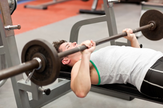 joven musculoso con levantamiento de pesas en un gimnasio