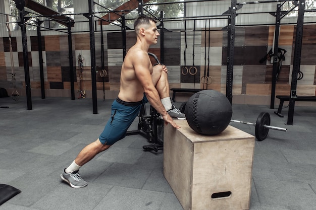 Joven musculoso practicando estiramientos musculares en un club de salud moderno