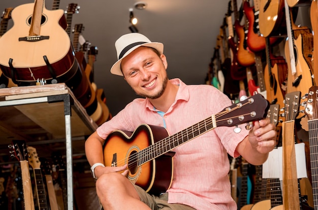 Joven músico afinando una guitarra clásica en una tienda de guitarras