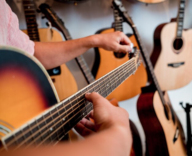 Joven músico afinando una guitarra clásica en una tienda de guitarras