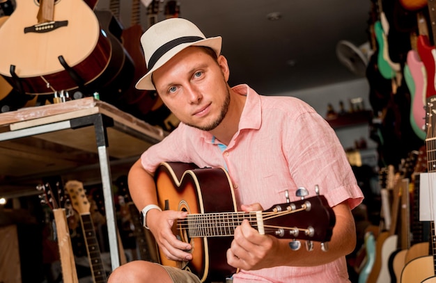 Joven músico afinando una guitarra clásica en una tienda de guitarras