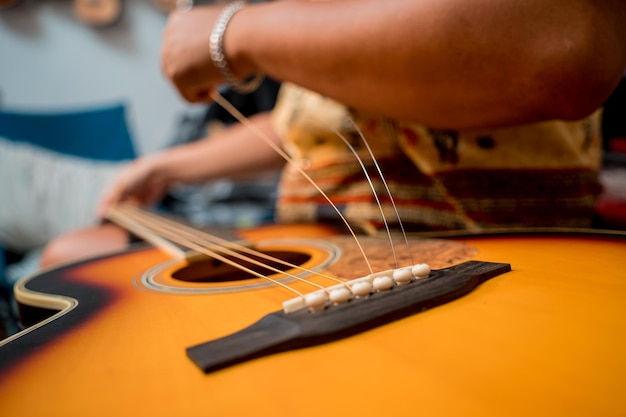 Foto joven músico cambiando cuerdas en una guitarra clásica en una tienda de guitarras