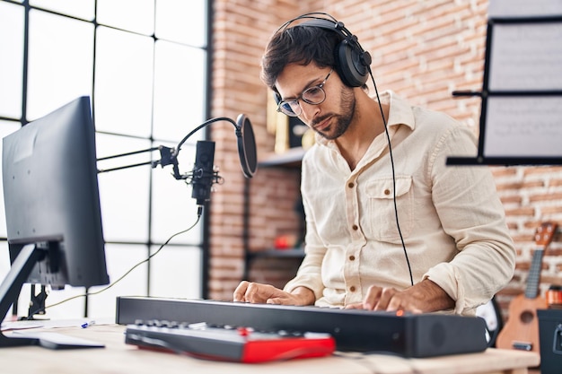 Joven músico hispano tocando el teclado del piano en el estudio de música