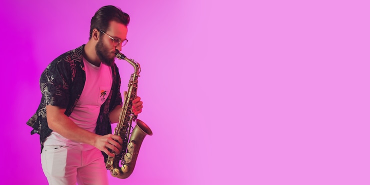 Foto joven músico de jazz caucásico tocando el saxofón en luz de neón, folleto con copyspace para anuncios