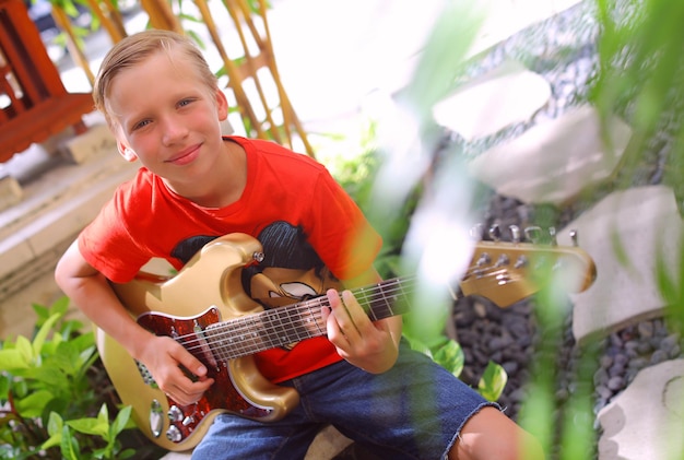 un joven músico un niño con una guitarra en el porche de la casa