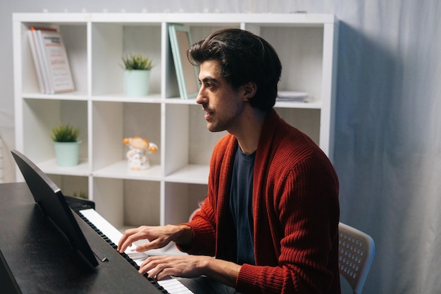 Joven músico talentoso tocando el piano en el estudio de casa durante la lección en el tiempo libre