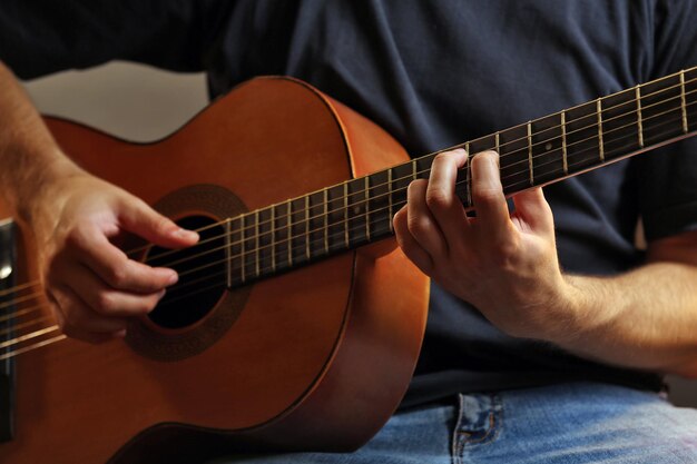 Joven músico tocando la guitarra acústica de cerca