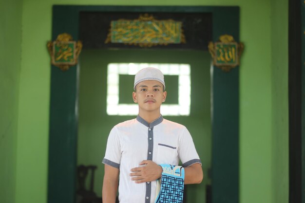 Foto joven musulmán asiático rezando en la mezquita con una alfombra de oración