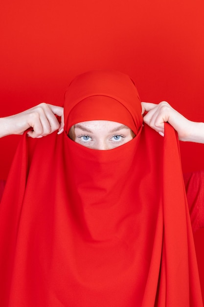 Joven musulmana asiática con hermosos ojos cubriendo su rostro con bufanda aislada de fondo blanco