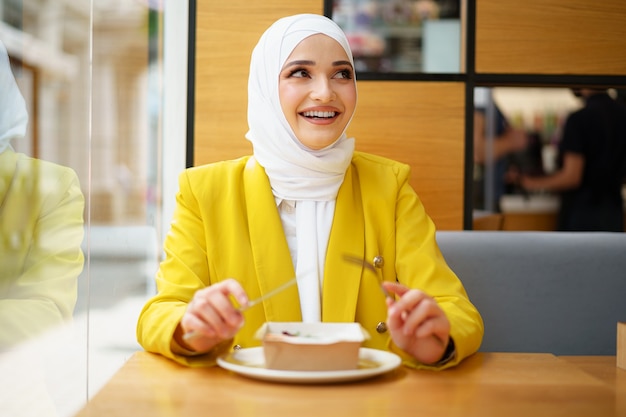 Joven musulmana en hijab almorzando en el café