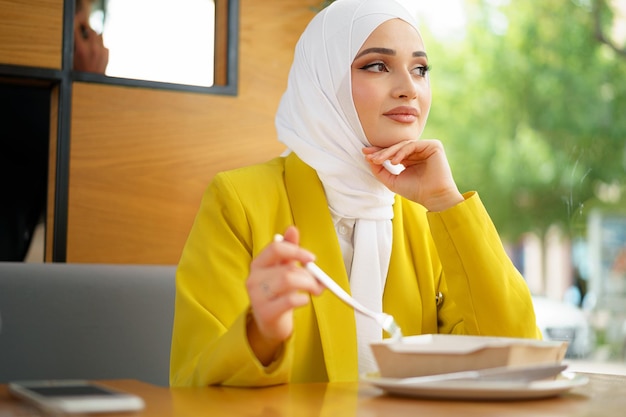 Joven musulmana en hijab almorzando en el café