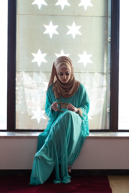 Joven musulmana con rosario rezando