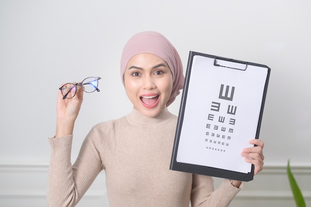 Una joven musulmana sosteniendo una prueba de gráfico de visión para medir la agudeza visual