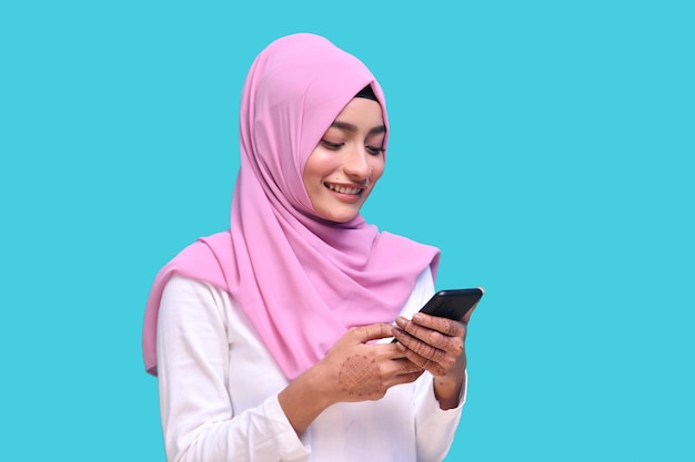 Joven musulmana vistiendo hijab rosa usando teléfono modelo paquistaní indio