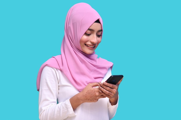 Joven musulmana vistiendo hijab rosa usando teléfono modelo paquistaní indio