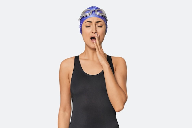 Foto joven nadadora profesional caucásica bostezando mostrando un gesto cansado cubriendo la boca con la mano