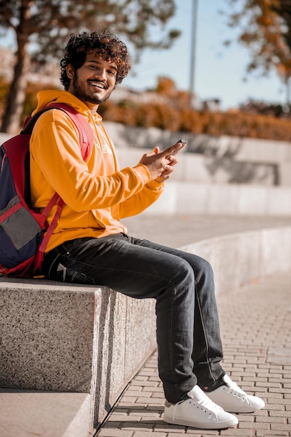 Joven de naranja con un teléfono en las manos