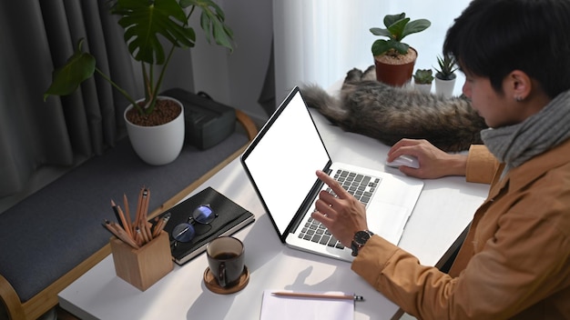 Joven navegando por internet en una computadora portátil en el lugar de trabajo