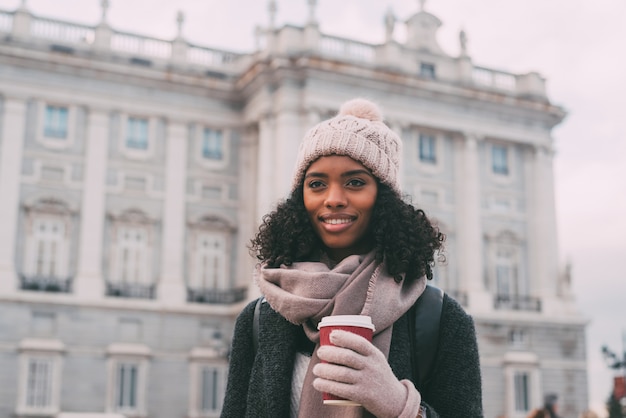 Joven negra bebiendo café vagando por las calles de Madrid en invierno