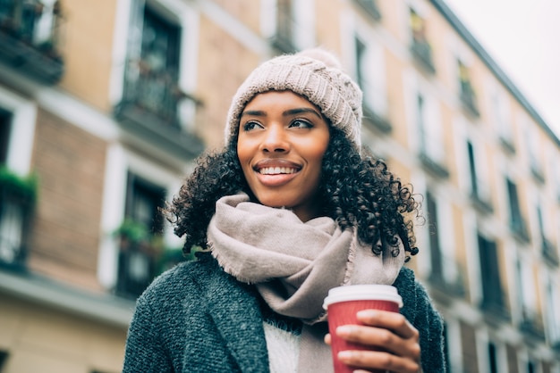 Joven negra bebiendo café vagando por las calles de Madrid en invierno