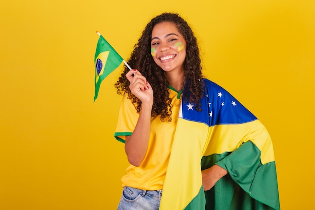 Foto joven negra brasileña fanático del fútbol ondeando bandera patriótica nacionalista