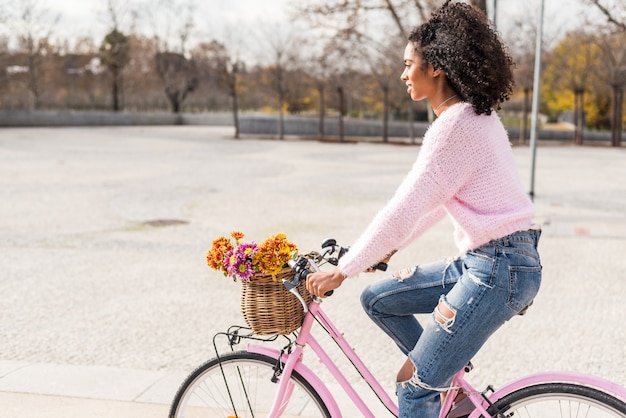 Foto joven negra montando una bicicleta vintage