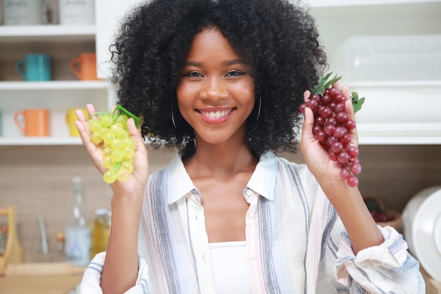 Joven negra con mujer de cabello afro preparando y comiendo fruta antes de hacer un batido