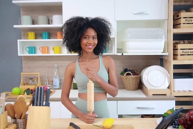 Joven negra con mujer de cabello afro preparando y comiendo fruta antes de hacer un batido