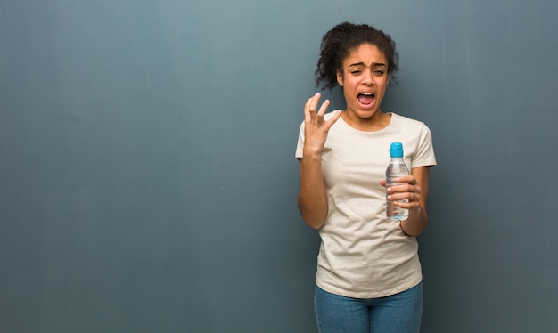 Joven negra muy asustada y asustada. Ella está sosteniendo una botella de agua.