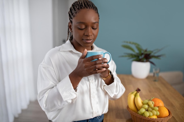 Una joven negra pacífica bebiendo café en casa