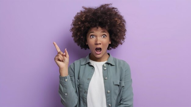 Una joven negra sorprendida señalando hacia arriba en el estudio.