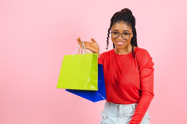 Joven negra sosteniendo bolsas de compras en el fondo rosa