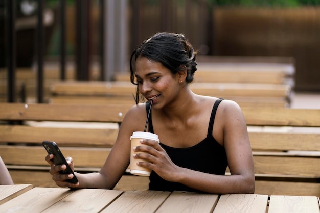 Una joven negra con una taza de café para llevar con un retrato al aire libre de paja negra