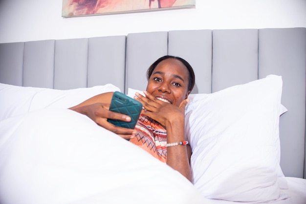 joven negra usando su teléfono en la cama