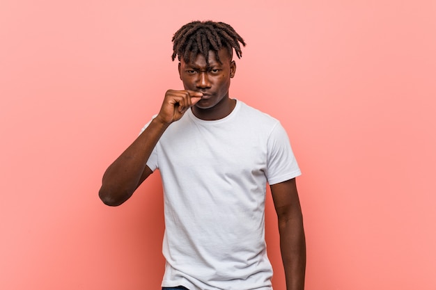 Joven negro africano con los dedos en los labios guardando un secreto.