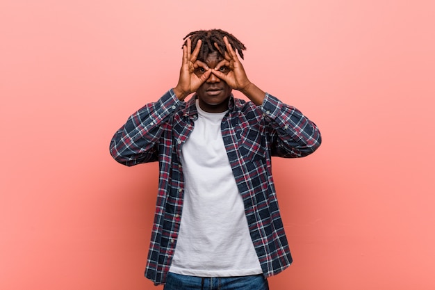 Joven negro africano que muestra bien firmar sobre los ojos