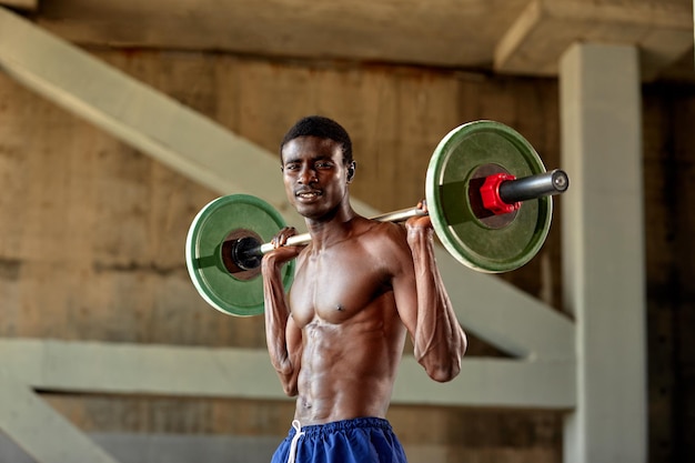 Joven negro atlético levantando una pesa pesada en un gimnasio al aire libre bajo el puente Concepto de estilo de vida saludable