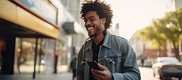 Joven negro con chaqueta de mezclilla caminando hablando por teléfono sonriendo mirando el área vacía Comunicación entre los millennials