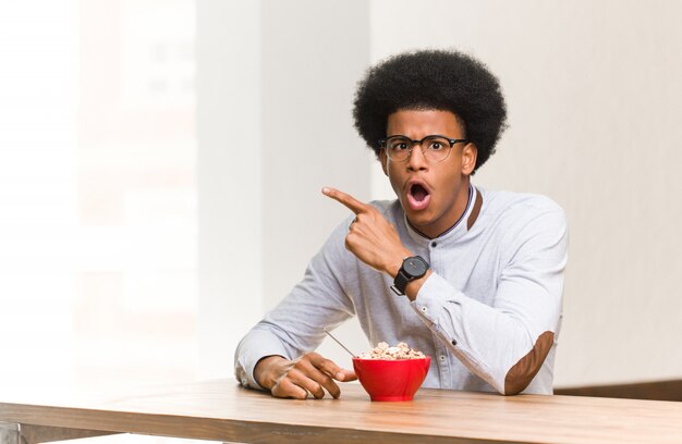 Joven negro desayunando apuntando hacia el lado