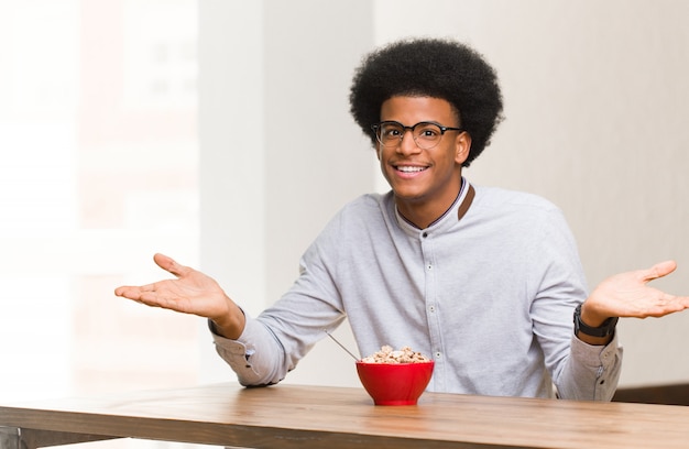 Joven negro desayunando invitando a venir