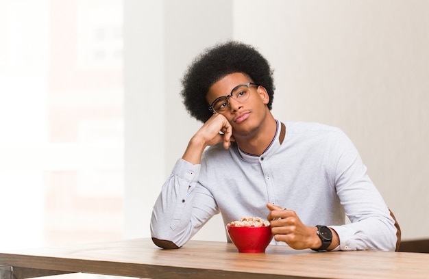 Joven negro desayunando pensando en algo, mirando hacia el lado