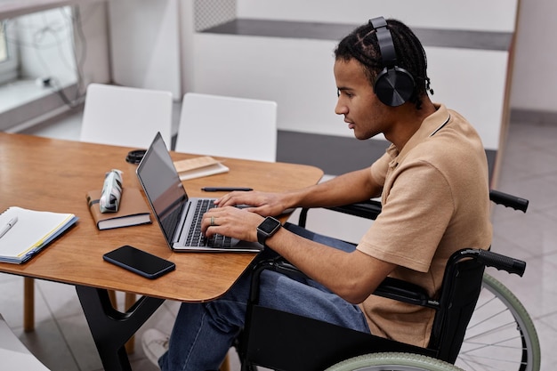 Joven negro con discapacidad usando una laptop en la universidad