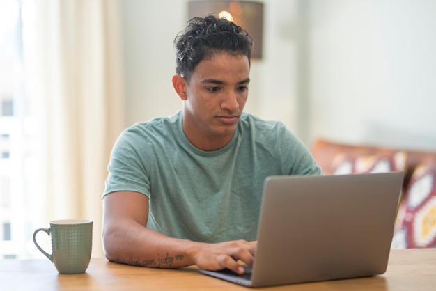 Joven negro moderno trabaja en casa con ordenador portátil navegando por la web. Personas de actividad laboral en línea en la mesa en la oficina de lugar de trabajo a domicilio. Concepto de negocio de trabajo inteligente