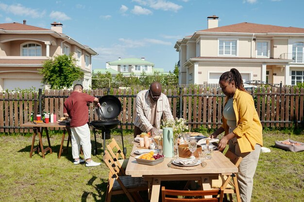 Joven negro y mujer sirviendo mesa con comida y bebidas caseras